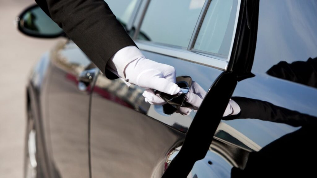 a chauffeur opening the door of a black car