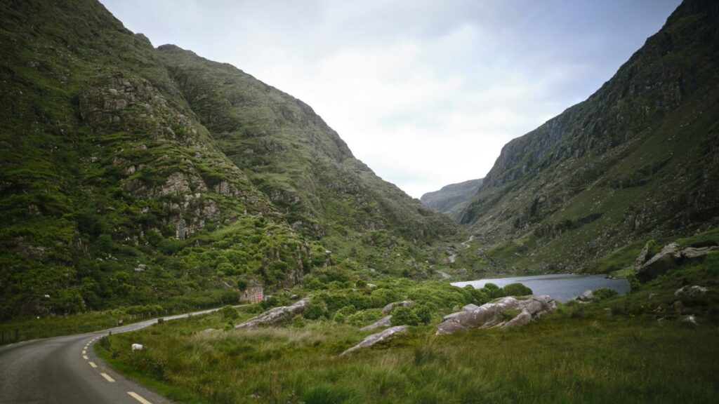 a winding road in the mountains with a lake in the middle