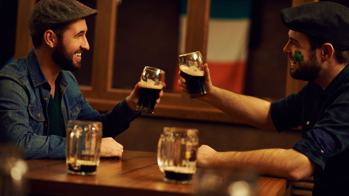 Two cheerful young men toasting with stout in an Irish Pub
