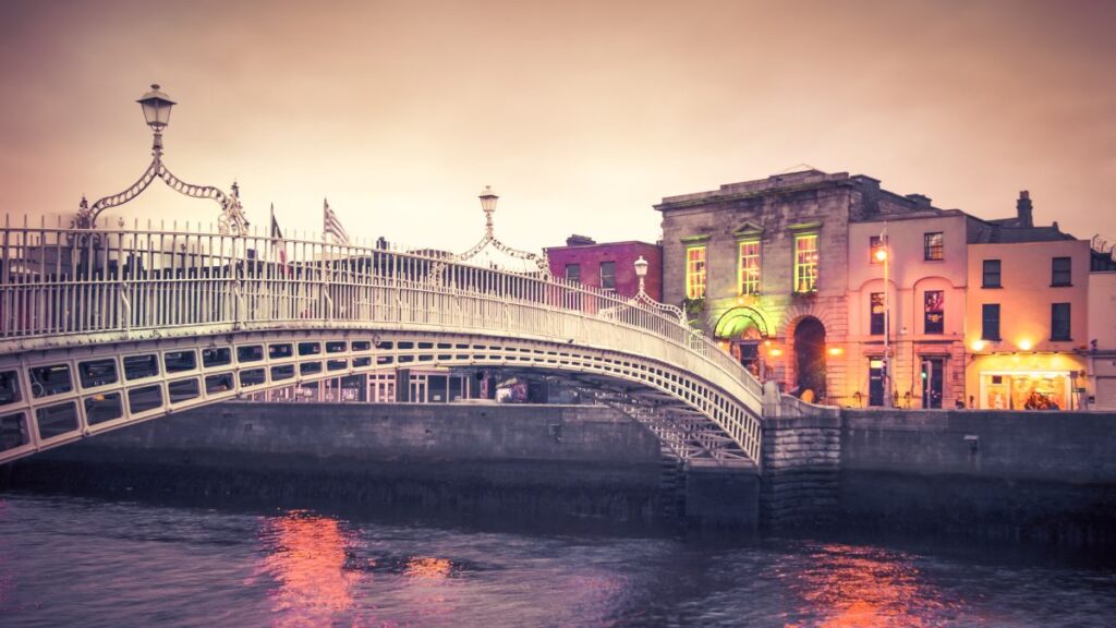 Vintage style historic Ha'penny Bridge and waterfront in Dublin, Ireland at dusk.