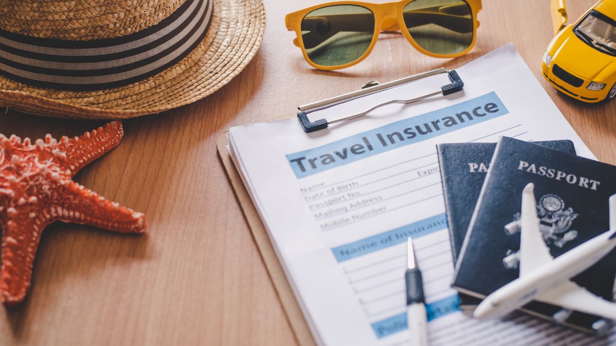 Travel insurance document with a passport and boarding pass on a wooden table.